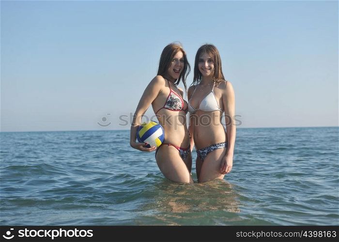 two hot girls posing in bikini posing at sea with volleyball ball
