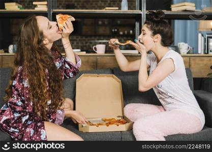 two hungry young women eating pizza