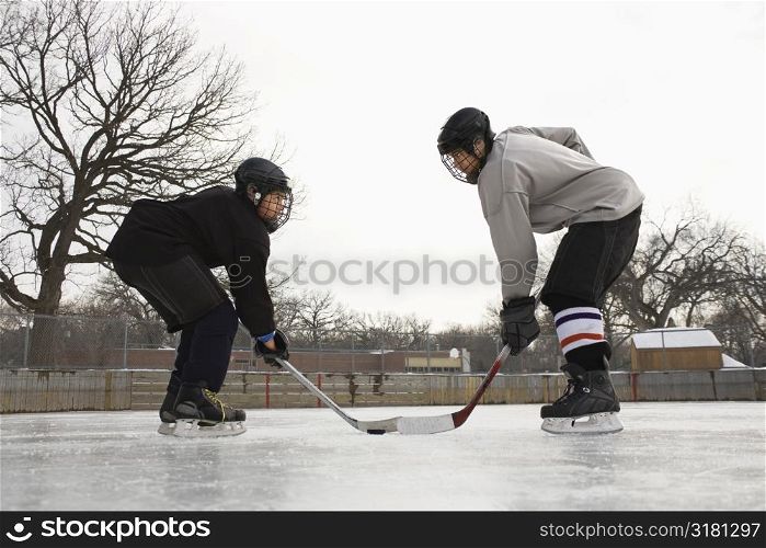 Two ice hockey player boys in uniform facing off on ice.