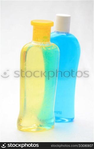 Two isolated shampoo bottles, yellow and blue