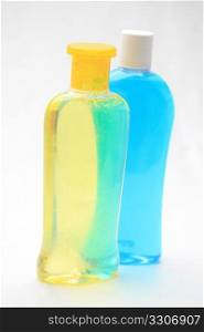 Two isolated shampoo bottles, yellow and blue