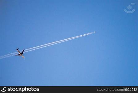 Two jet airplanes cross on blue sky with condensation trail.