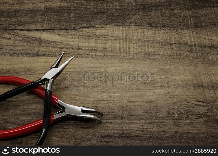 Two jewelry pliers on a wooden background.