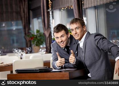 Two joyful businessmen at restaurant celebrate the transaction
