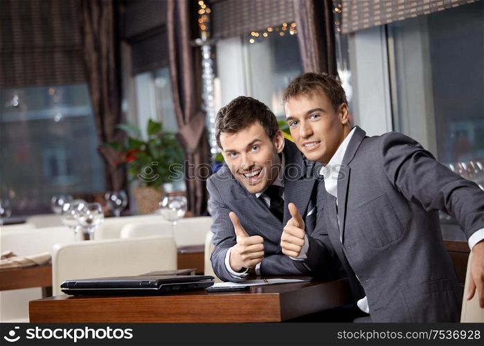 Two joyful businessmen at restaurant celebrate the transaction