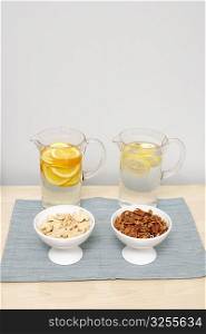 Two jugs of lemonade with two bowls of nuts