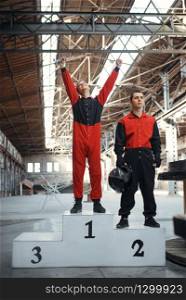Two kart racers on podium, winners, karting auto sport indoor. Speed race on close go-kart track with tire barrier. Fast vehicle competition, active hobby