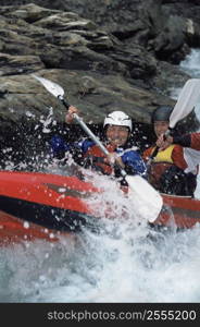 Two kayakers rowing in rapids and smiling