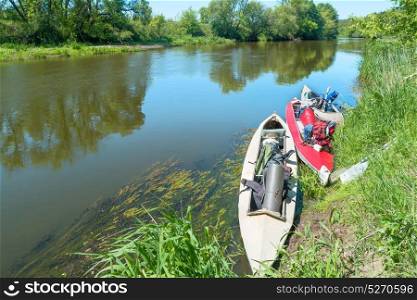 Two kayaks standing in water near river bank with no people