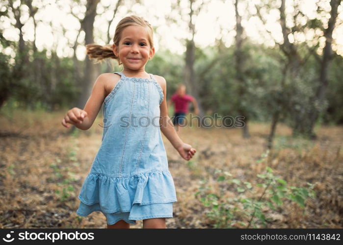 Two kids play running in the forest