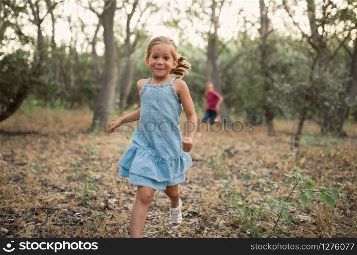 Two kids play running in the forest
