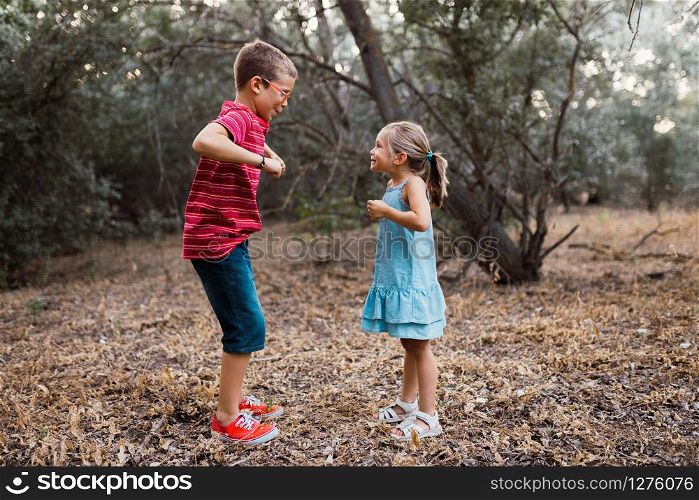 Two kids playing and dancing in the forest