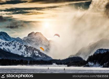 Two kite surfing on a frozen lake in the high mountains