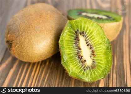Two Kiwi Fruits sit on the cutting board on cut in half