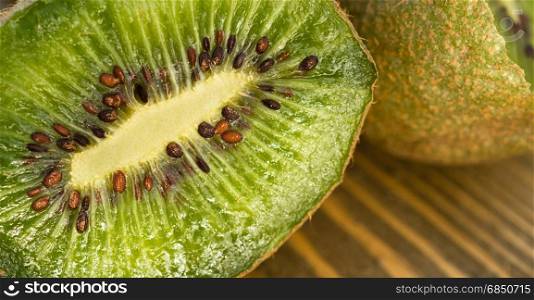 Two Kiwi Fruits sit on the cutting board on cut in half showing inside close up
