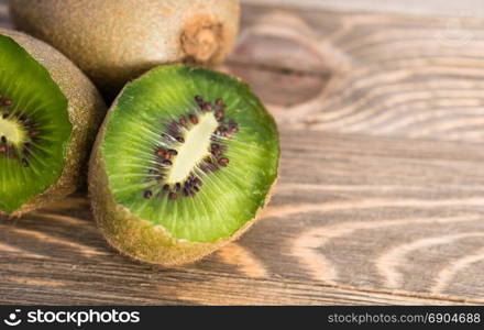 Two Kiwi Fruits sit on the cutting board on cut in half