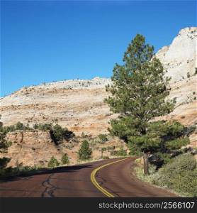 Two lane road winding along desert cliffs in Zion National Park, Utah.