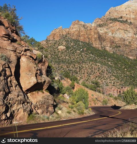 Two lane road winding through rocky desert cliffs in Zion National Park, Utah.