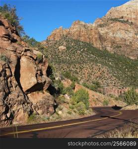 Two lane road winding through rocky desert cliffs in Zion National Park, Utah.