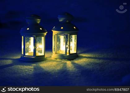 Two Lantern with burning candle on snow in the evening. Two Lantern with burning candle on snow in the evening.