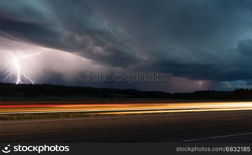 Two lightning bolts appear in this scene as a car passes in Yellowstone National Park