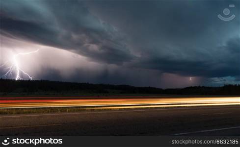 Two lightning bolts appear in this scene as a car passes in Yellowstone National Park