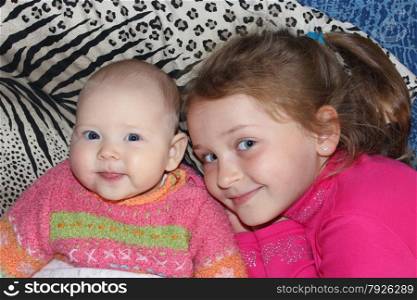 two little babies sisters lying on the bed and smiling