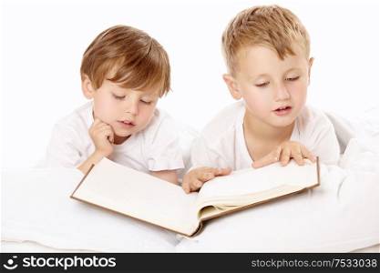 Two little boys read the book in the bed, isolated