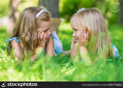 Two little cute girls on lawn in the park