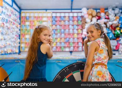 Two little girlfriends playing in kids shooting gallery, playground in entertainment center. Play area indoors, playroom