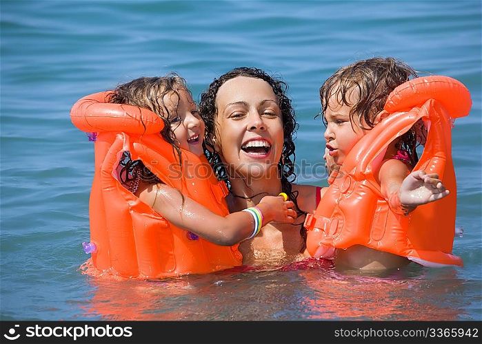 two little girls bathing in lifejackets with young woman in pool on resort