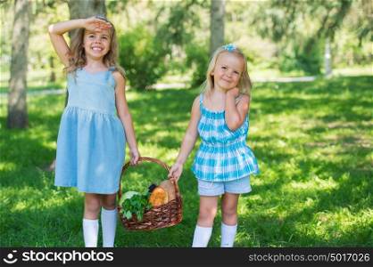 Two little girls carrying basket with organic food for picnic, outdoors