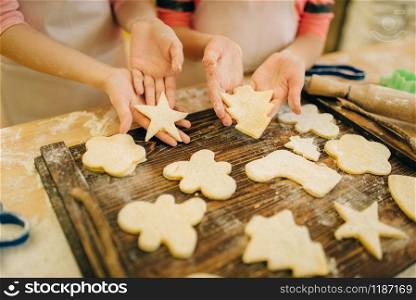 Two little girls chefs spread out cookies on a wooden board, bakery preparation on the kitchen, funny bakers. Kids cooking pastry and having fun, children cooks preparing cake. Little girls chefs spread out cookies on board