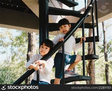 Two little girls climbed the stairs to the tower in the playground. Family outdoor recreational activity.