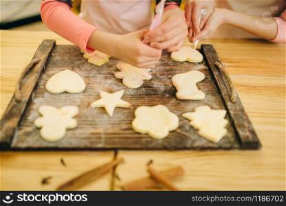 Two little girls cooks preparing to send cookies in the oven, bakery preparation on the kitchen, funny bakers. Kids cooking pastry and having fun, children chefs prepares cake. Girls cooks preparing to send cookies in the oven