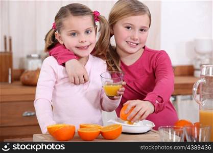 two little girls drinking orange juice