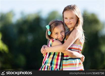Two little girls hugging each other in the park. Childhood friendship. Sisters.. Two little girls hugging each other in the park.