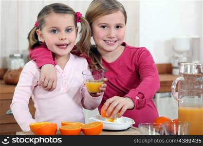 Two little girls making orange juice.