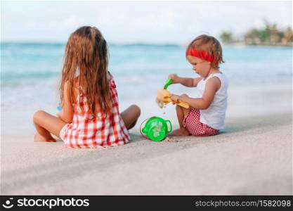 Two little girls making sand castle on the white tropical beach. Two kids making sand castle and having fun at tropical beach