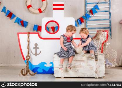 Two little girls play with seashells, sea theme.