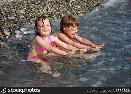two little girls sit in sea
