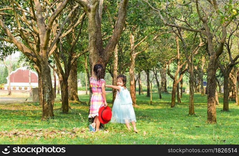 Two little sisters playing in the park tree outdoor. Summer concept