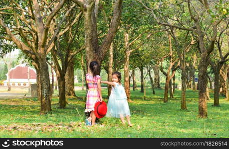 Two little sisters playing in the park tree outdoor. Summer concept