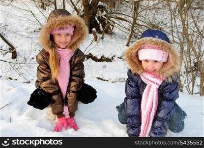 Two little sisters playing with snow outdoors