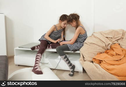Two little sisters using tablet in bedroom