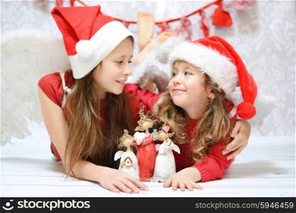 Two little sisters with small toy angels