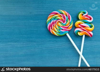 Two lollipops with many colors in a spiral on a wooden background