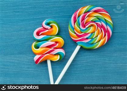 Two lollipops with many colors in a spiral on a wooden background