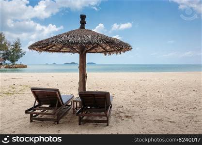 Two lounge chairs and a sunshade umbrella on the tropical beach
