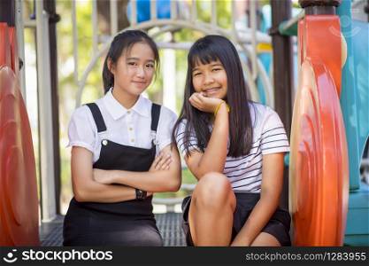 two lovely asian teeenager relaxing in children play ground